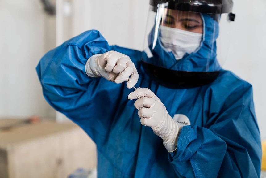 An Australian Clinical Laboratories worker places a nasal swab into a vial for COVID-19 testing.