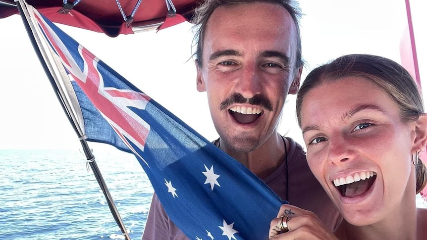Couple on boat waving Australian flag