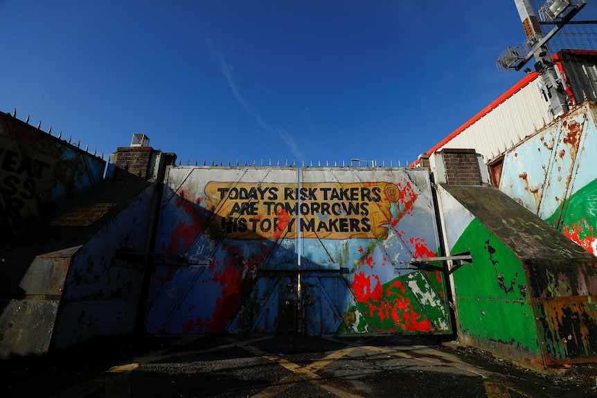 The words Today's risk takers are tomorrows history makers" painted on the peace wall gate in Belfast, Northern Ireland