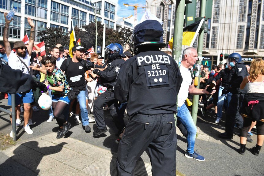 Participants of a demonstration against the Corona measures break through a police chain in Berlin.