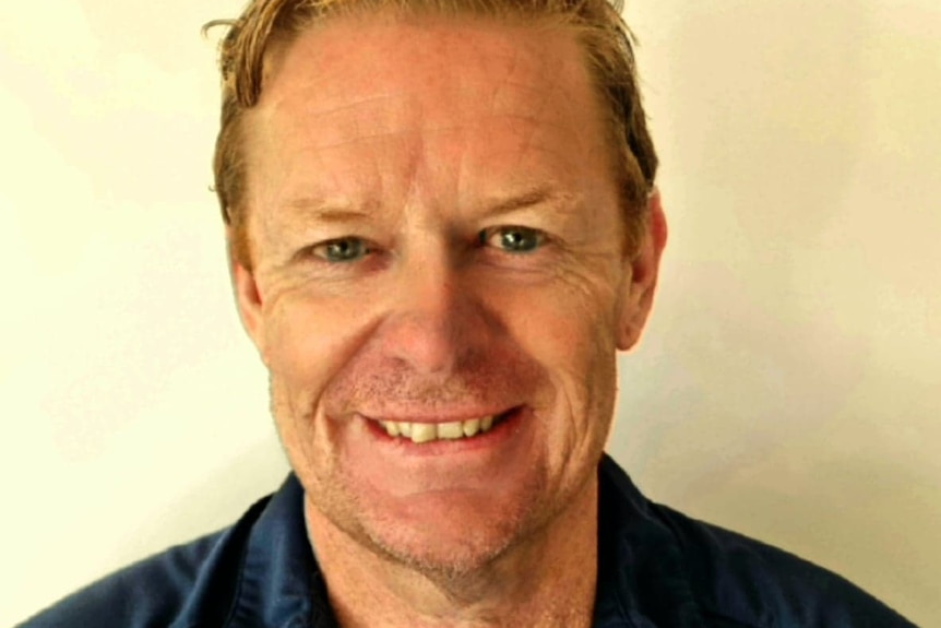 portrait photograph of Richard Murphy in front of blank wall wearing SANFL polo