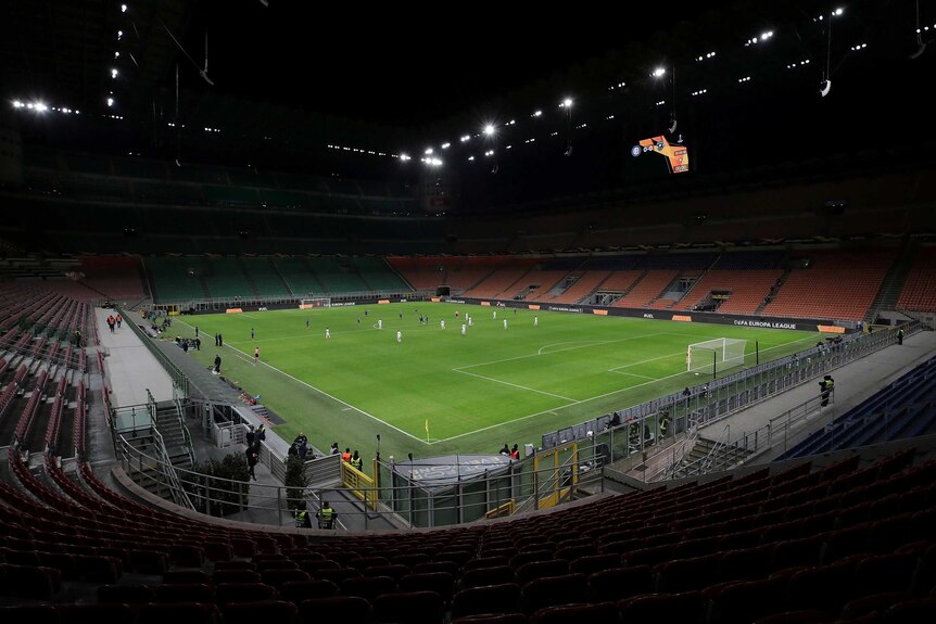 Seats are empty at the San Siro Stadium as football players start their match.