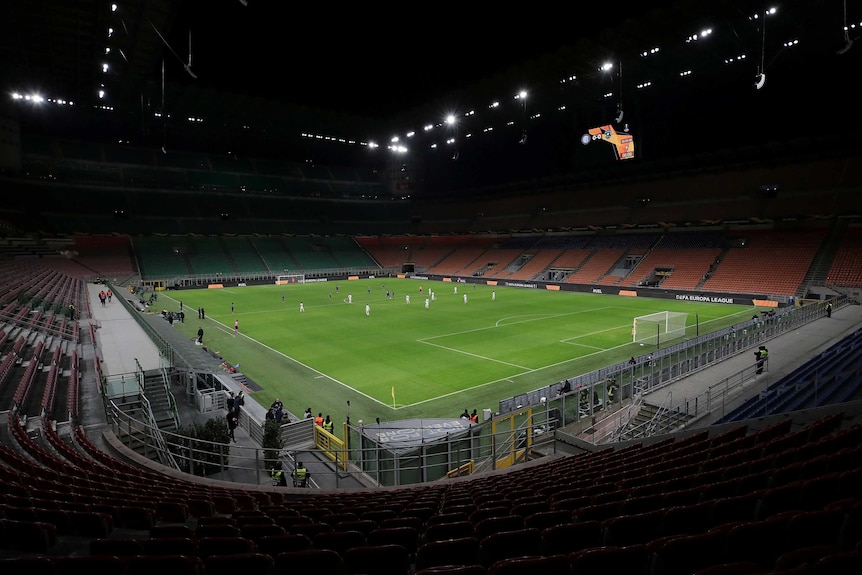 Seats are empty at the San Siro Stadium as football players start their match.