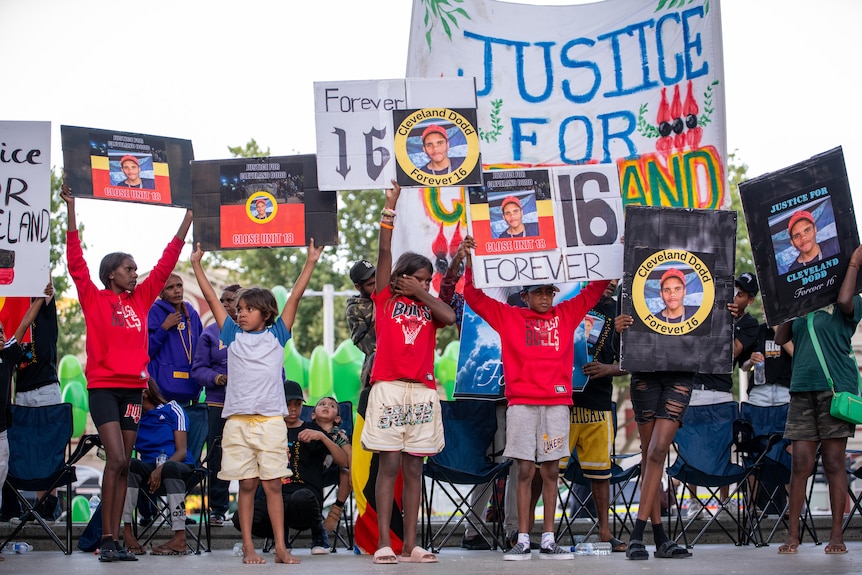 A group of children holding signs reading "Justice" and "Forever 16"