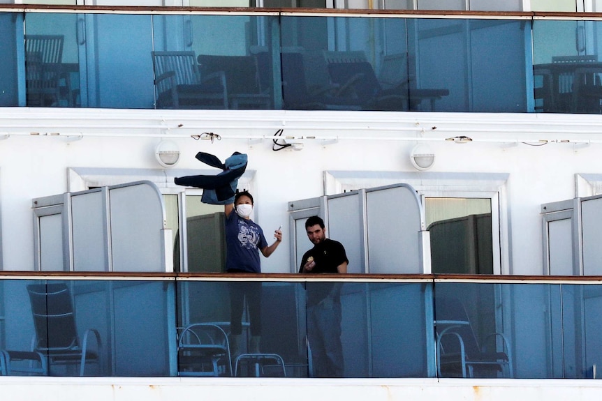 A woman waving her jacket around on the deck of a cruise ship