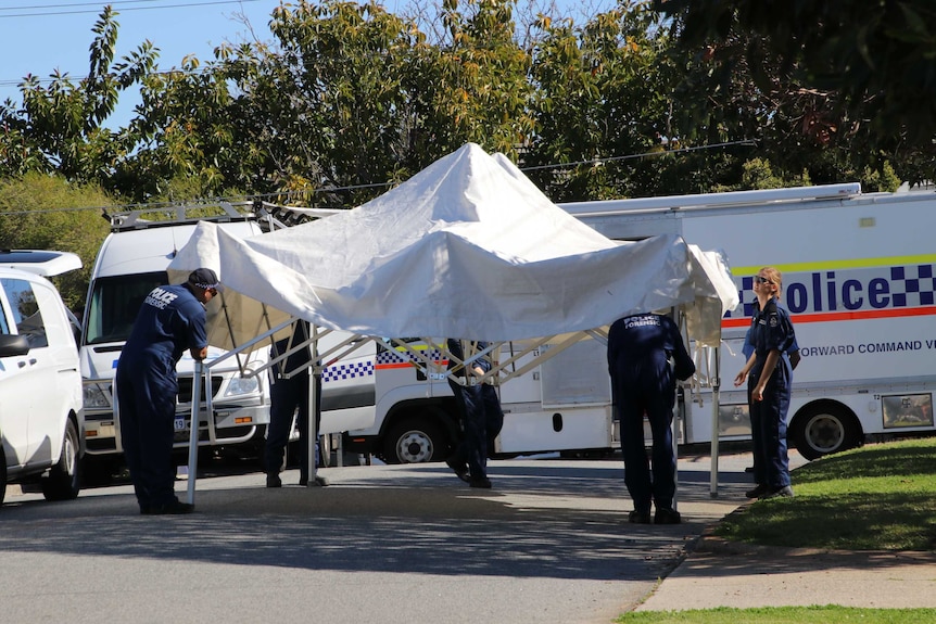 Forensic police work at a site where five people, including children, have been found dead.