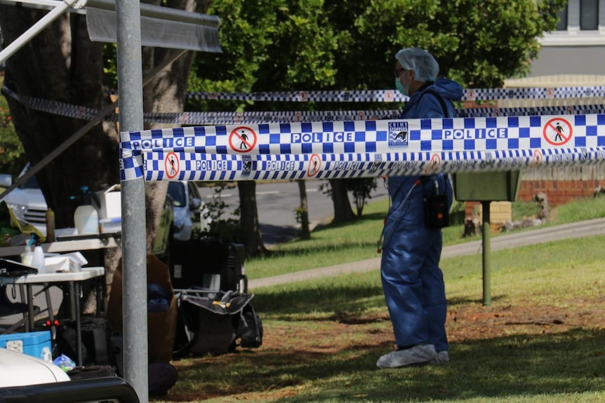 A forensic officer at the back of a police vehicle outside a house at Bracken Ridge.