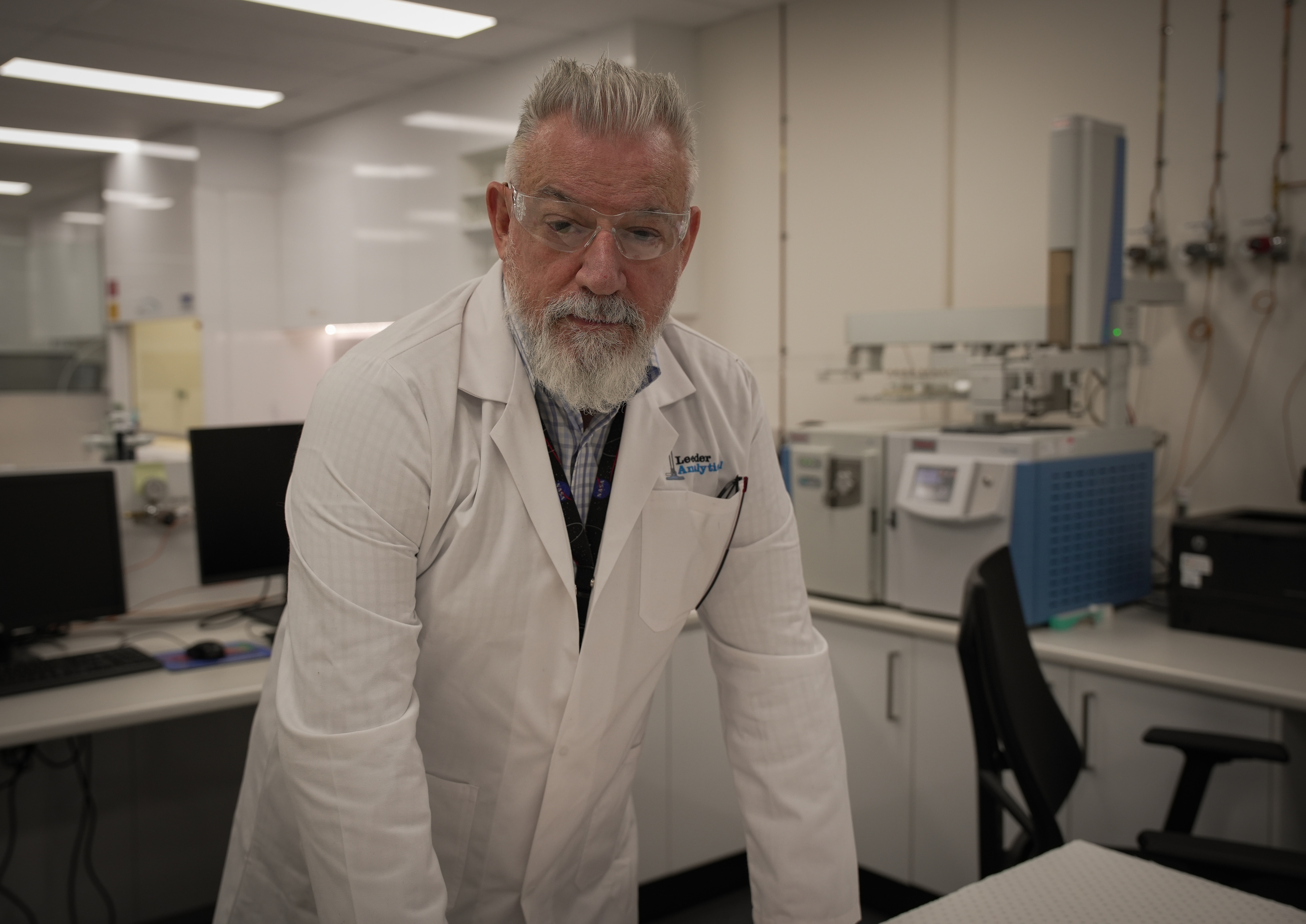 A man in a white lab coat standing in a laboratory.