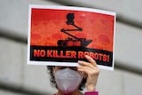 A  person holds a red sign that says, 'no killer robots'. 