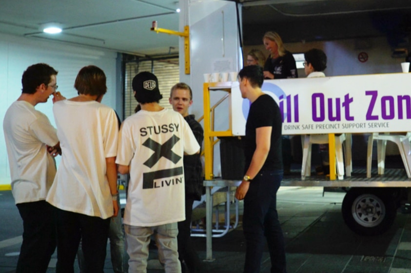 Group of young men standing outside a mobile caravan with sign that says Chill Out Zone.