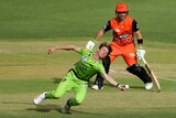 Brendan Doggett dives and clutches on to the ball as a Scorchers batsman looks on.