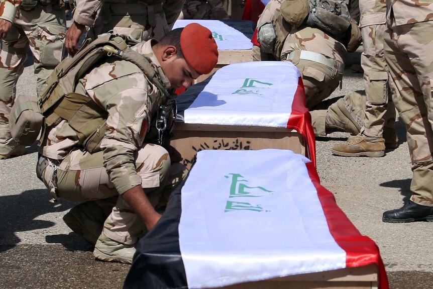 Iraqi soldiers transport coffins in Baghdad after their remains were exhumed from mass graves in Tikrit