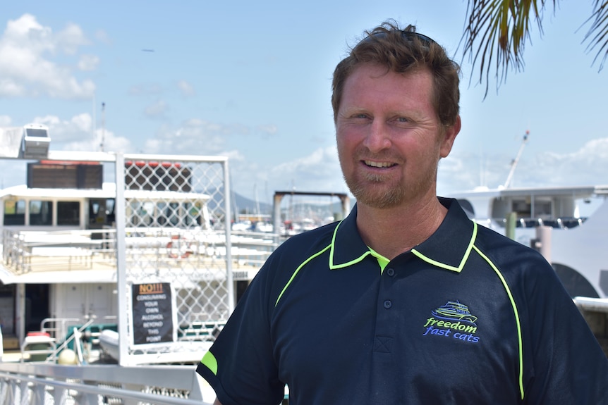 A man standing in front of a boat at a marina