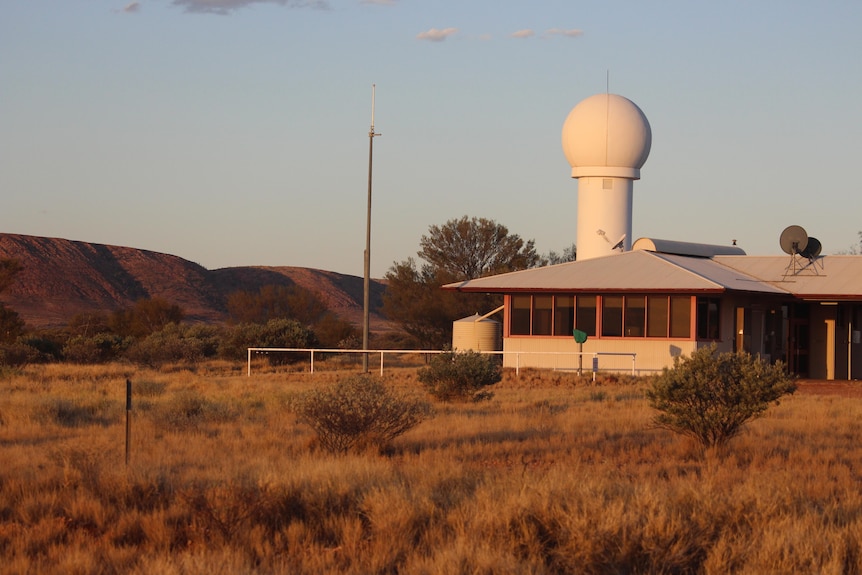 Giles Weather Station pictured at sunset with the glowing Rawlinson Ranges behind.
