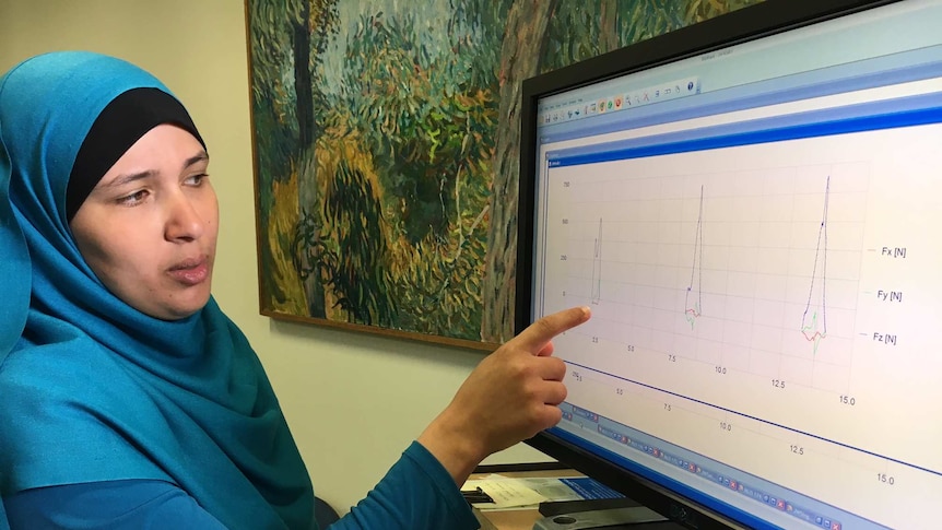 A woman studies a line graph on a computer screen.