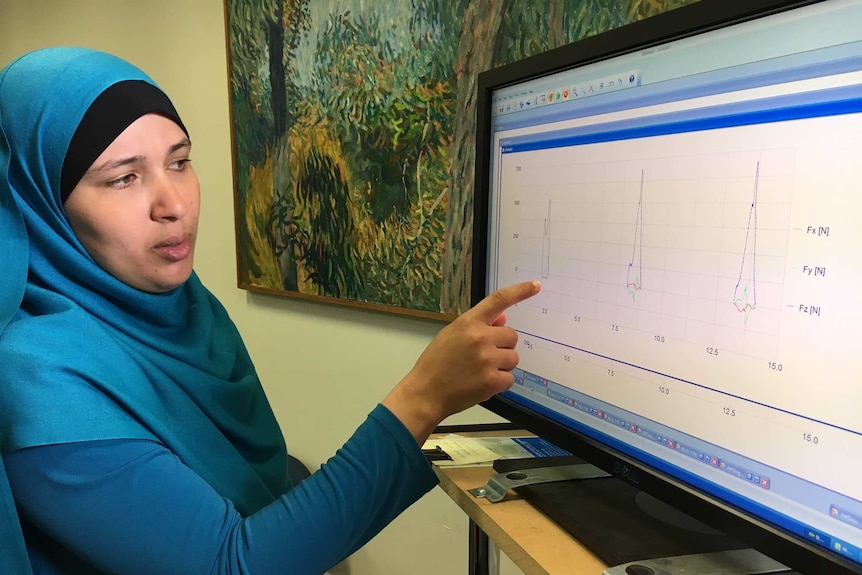 A woman studies a line graph on a computer screen.