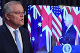 Australian Prime Minister Scott Morrison speaks at a podium while US President Joe Biden appears on a TV screen.