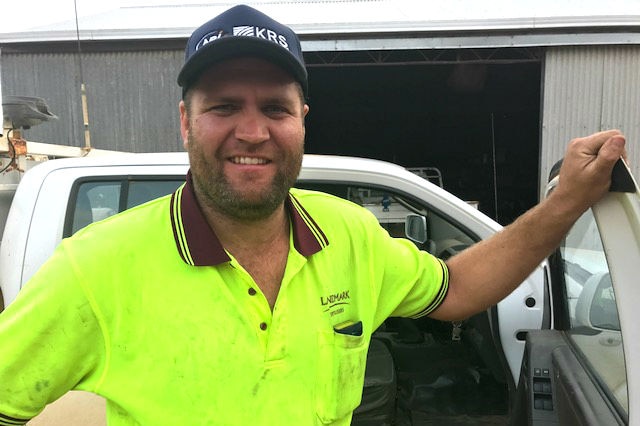 Jason Jones standing next to a car with one arm resting on an open door.