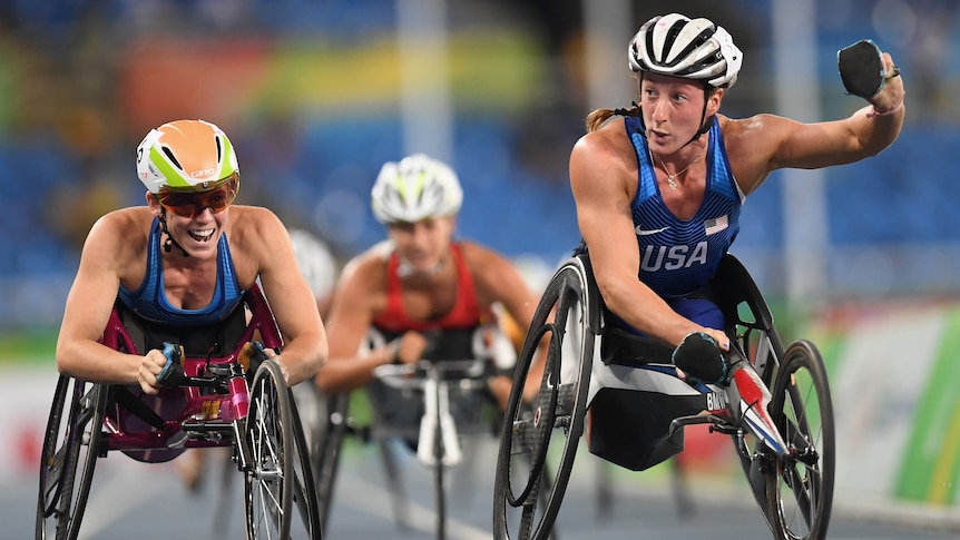 Dos atletas estadounidenses en silla de ruedas celebran después de cruzar la línea para llevarse el oro y el bronce en una carrera de 1.500 m.