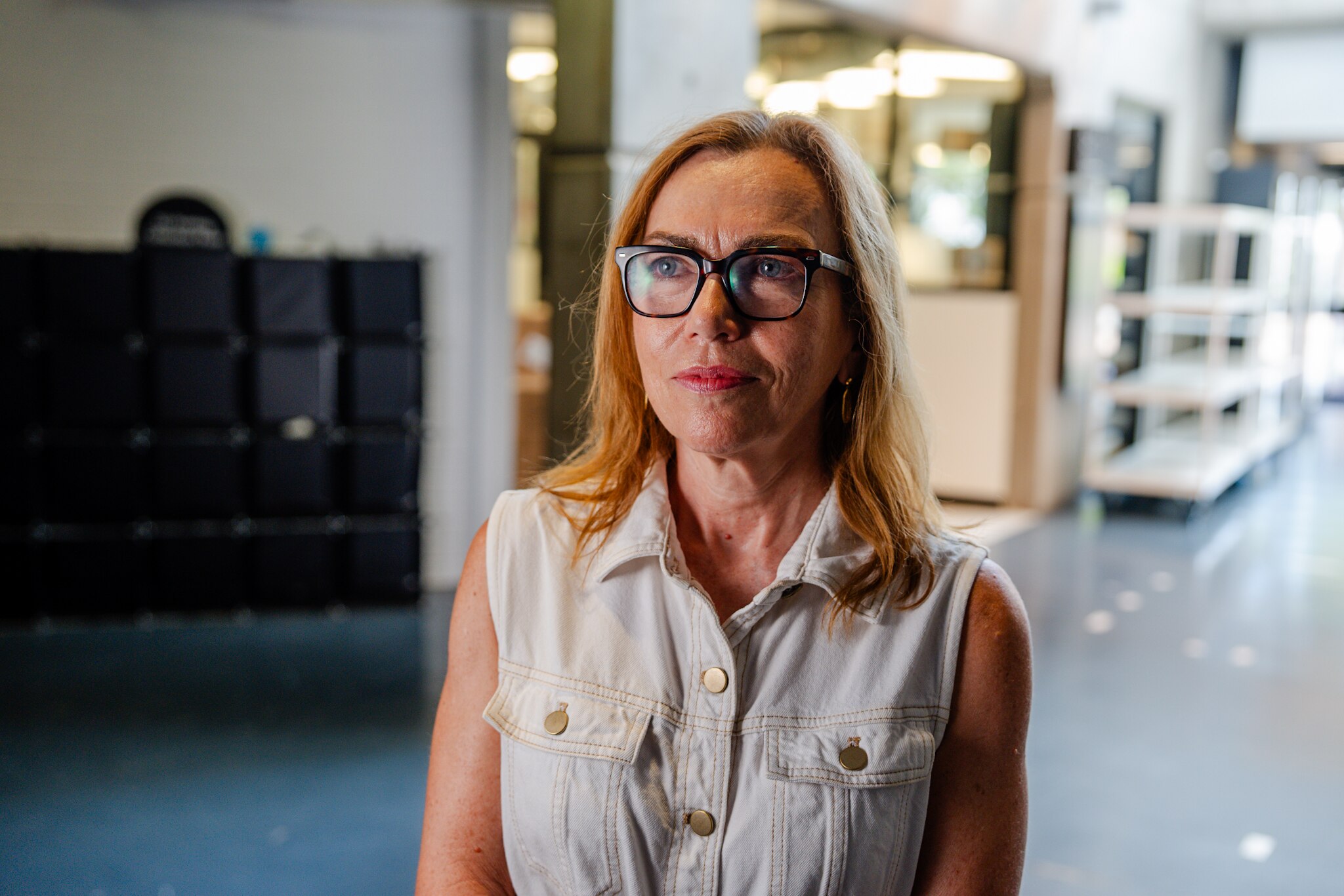 University of Sydney Professor Nicole Gurran wears glasses and stands indoors as she looks off into the distance.