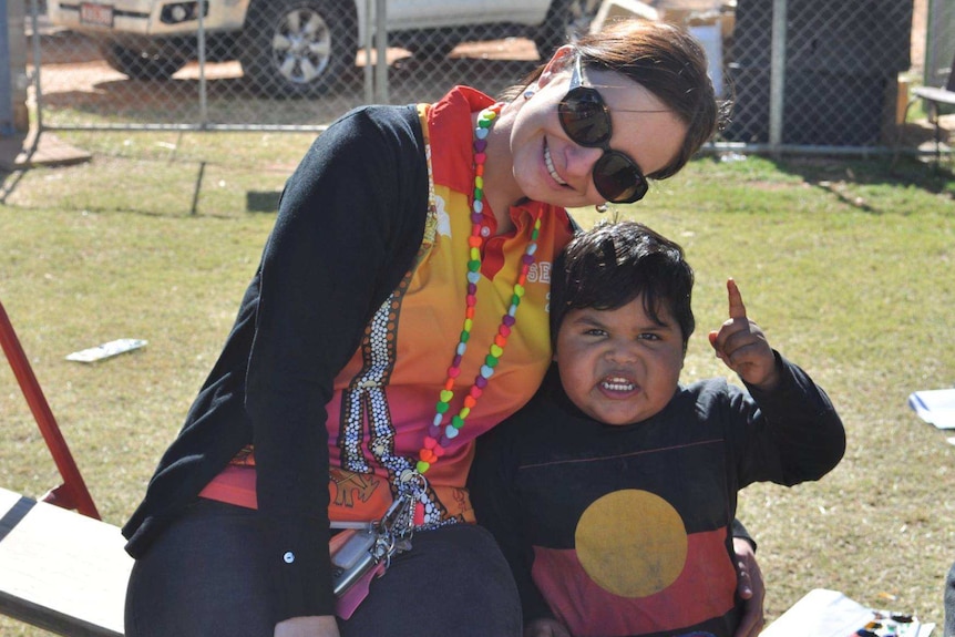 Woman and small boy sit together on grass