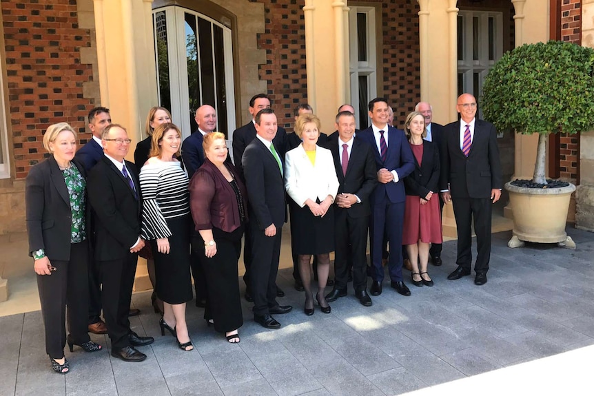 A wide shot of WA Premier Mark McGowan and his 17 ministers standing for a photo outside Government House.