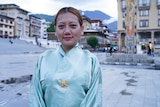 A close up of a smiling woman wearing a traditional dress on a Bhutanese square.