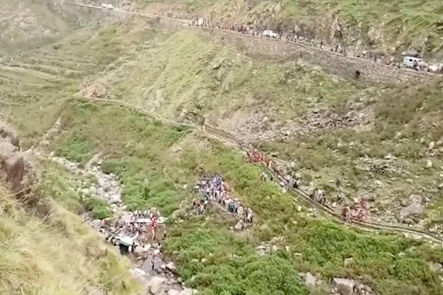 People at the bottom of a gorge where a bus has crashed
