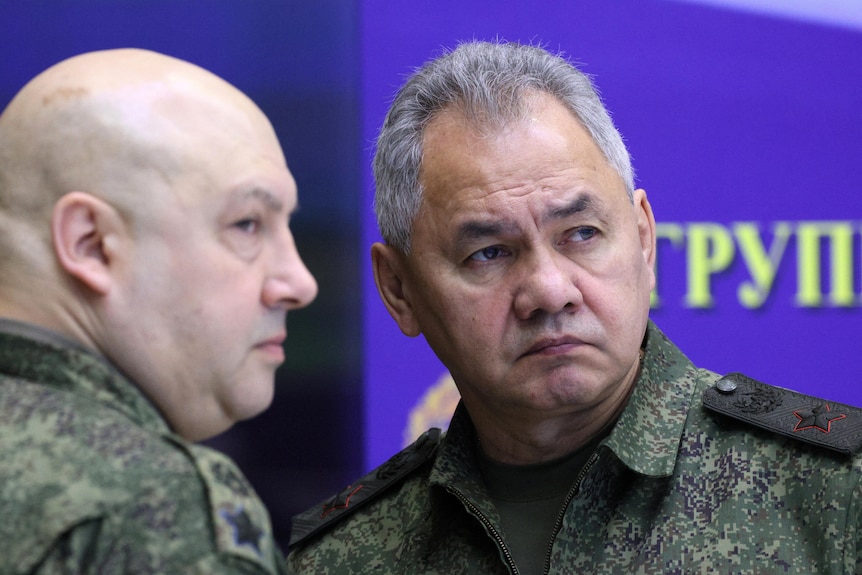 Sergei Shoigu in camoflauge gear speaking to a military staffer