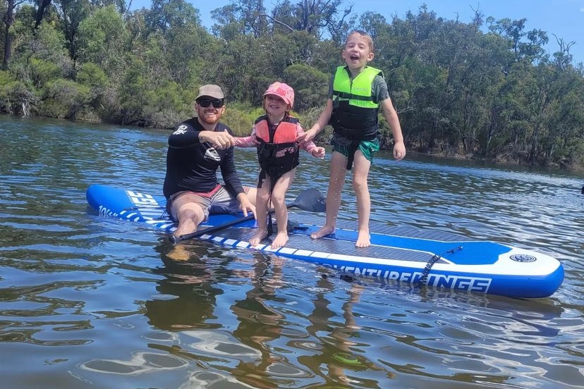 A man and two small children on a kayak in a river