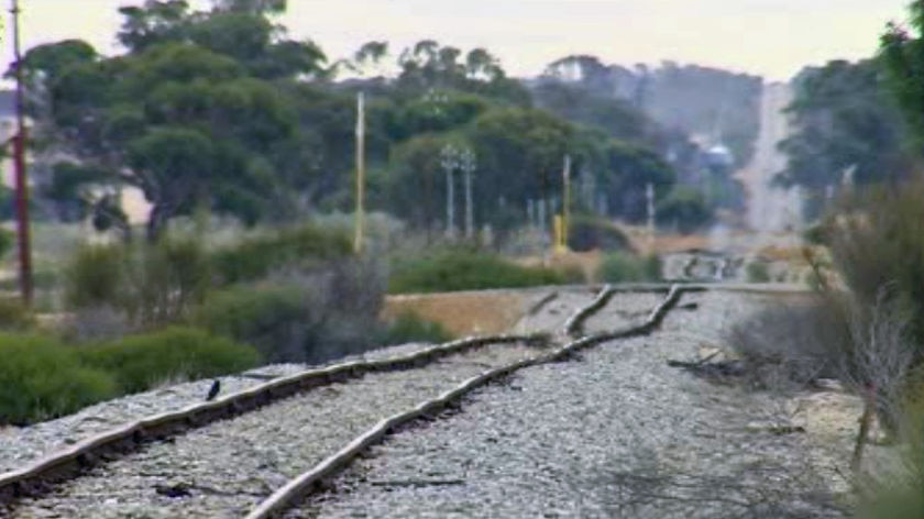 Rural rail network with line running across crossing and up into hill, no train