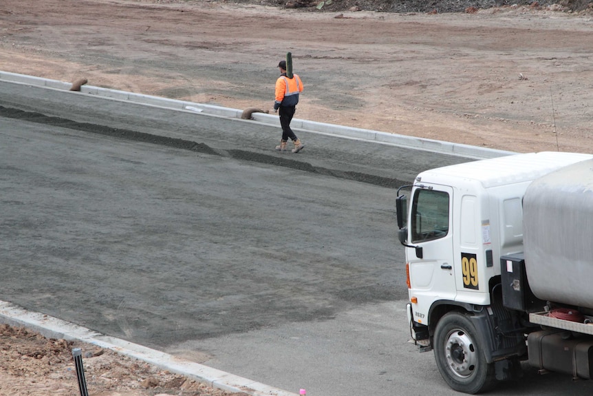 A man in hi-vis walks along a new unpaved road