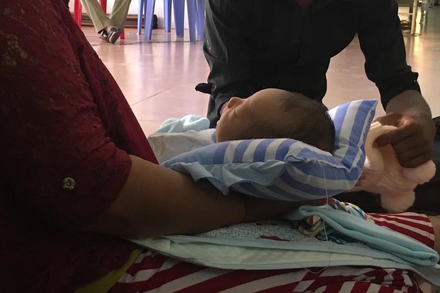 A close up of a child in its grandmother's arms.