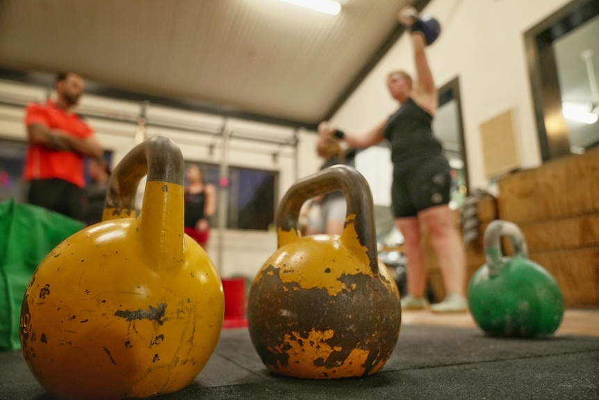 A close up of kettlebells, with people using them in the background.