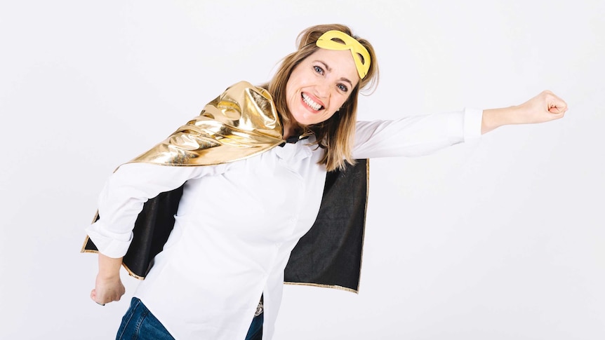 A woman wearing a gold cape and white shirt with one arm outstretched