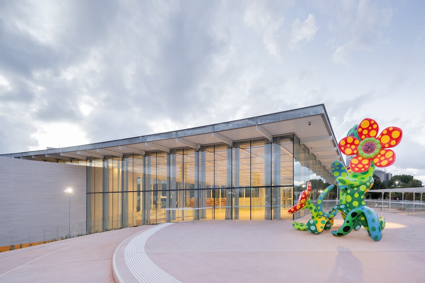 A large, brightly coloured sculpture of flowers stands outside a building lined with large windows