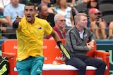 Nick Kyrgios, appearing angry, points at someone across the court.