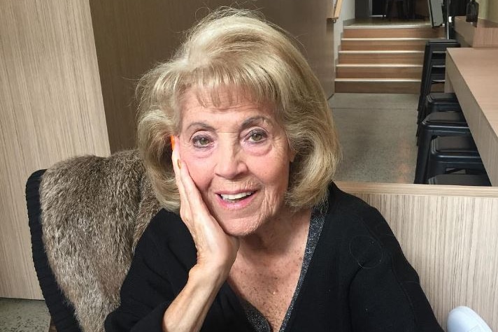 Lillian Frank smiles, resting her head on one hand as she sits in a restaurant.