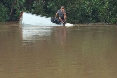 Adrian Hastwell-Batten sits on his car which sank in floodwaters near Bundaberg yesterday.