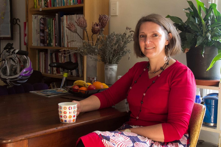 Nicole Thornton sits at her dining table in her Dulwich Hill apartment