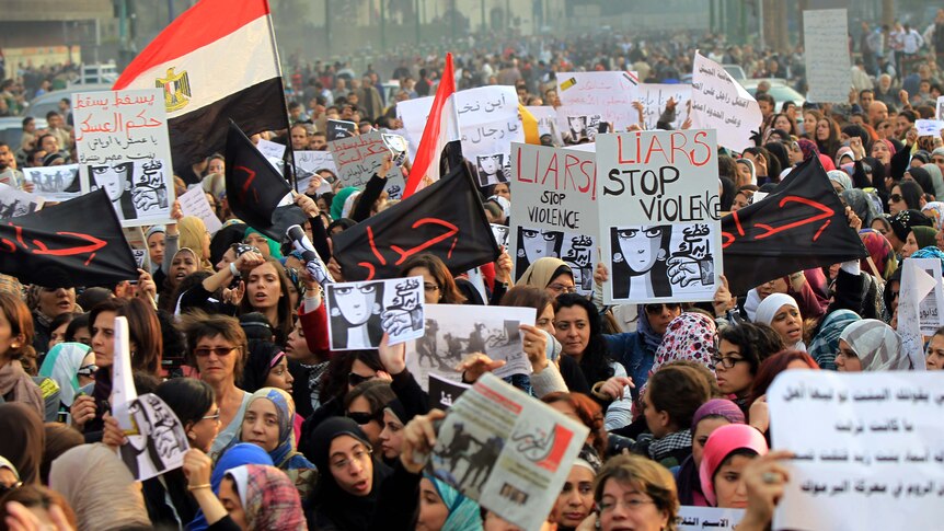 Egyptians hold signs during a protest in downtown Cairo to denounce the military's attacks on women