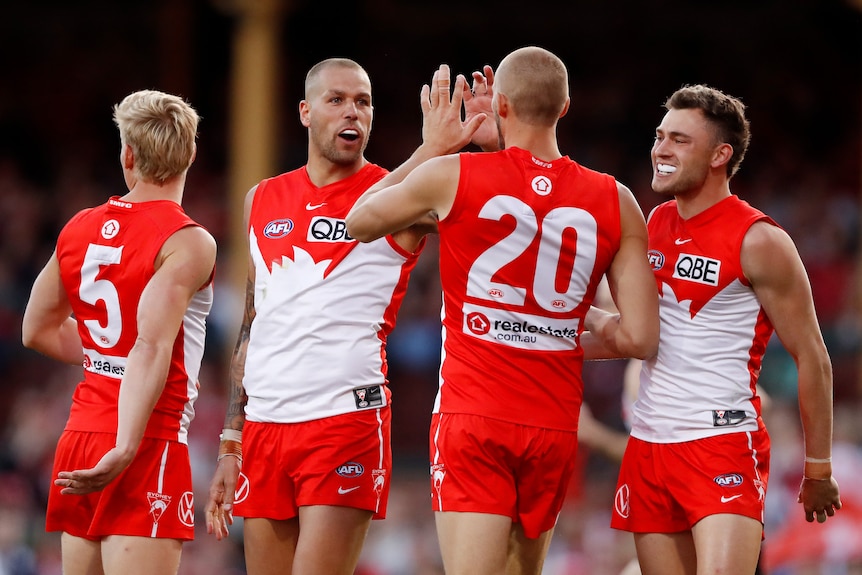 Four Sydney Swans AFL players congratulate each other following a goal against Collingwood.
