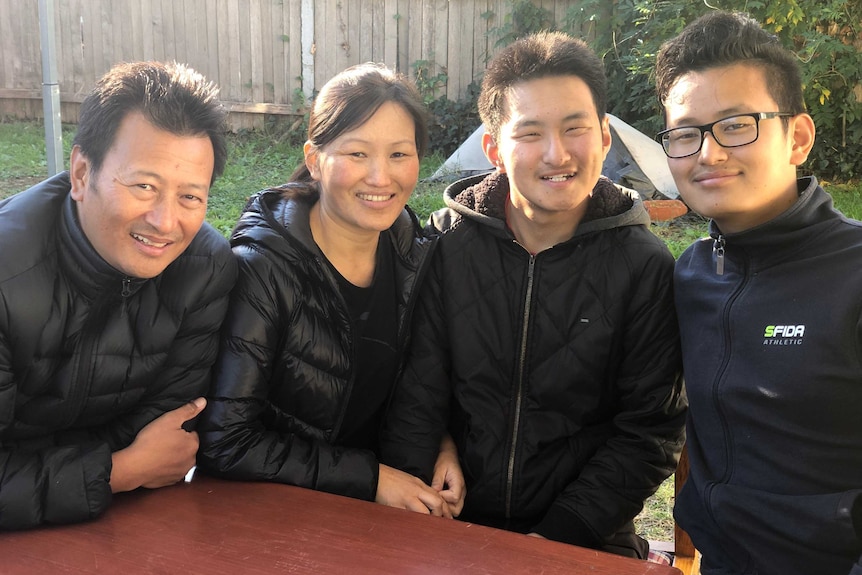 A father, mother and their two sons smile as they pose for a photograph