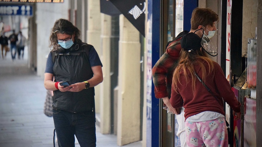 Customers in masks queue outside a shopfront in Sydney lockdown.