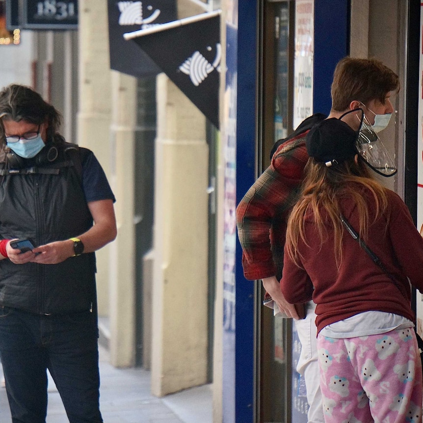 Customers in masks queue outside a shopfront in Sydney lockdown.