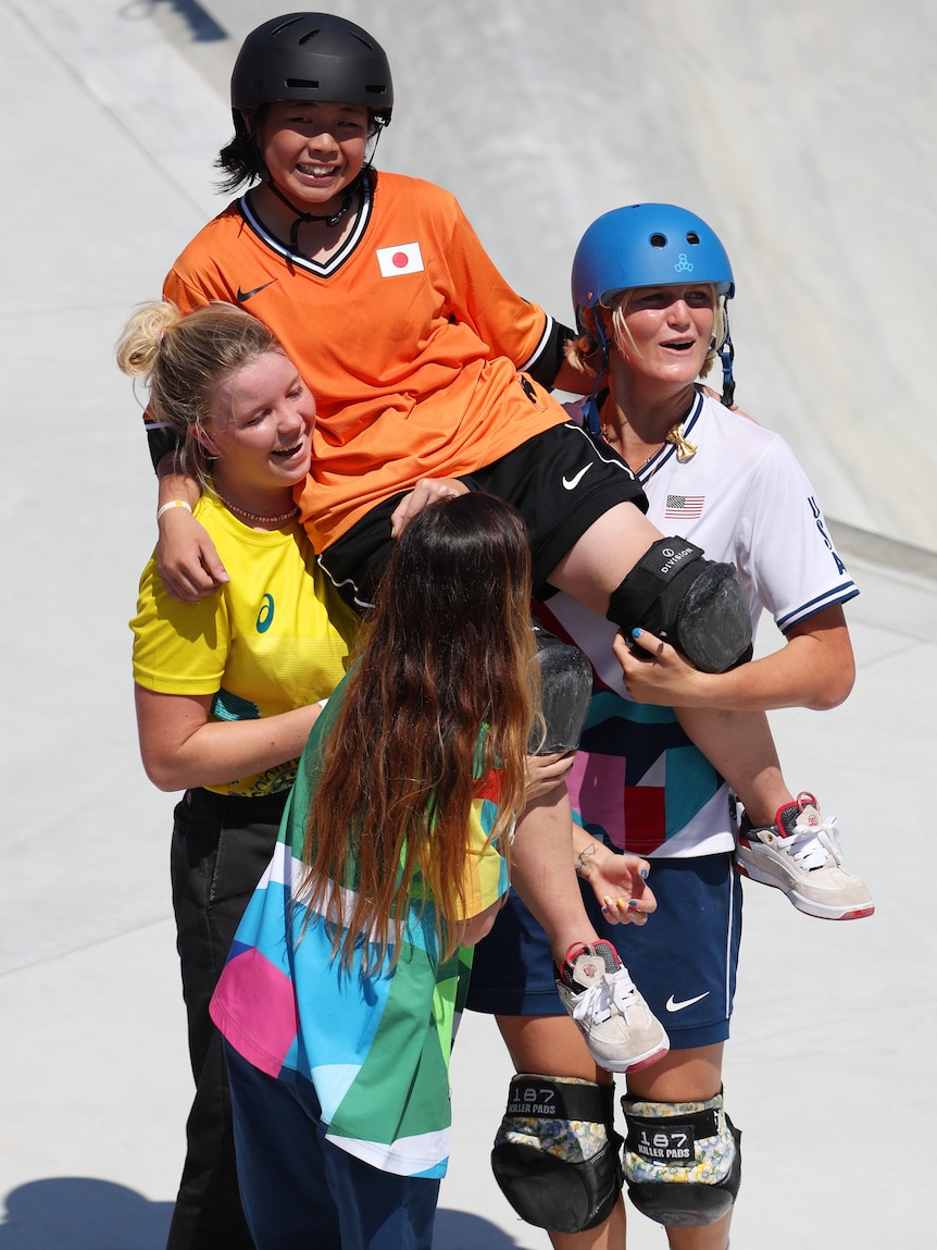 Olympic skateboarder lifting up fellow competitor after the final