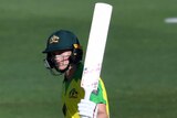 An Australian batter raises her bat with her left arm after scoring a half-century in a women's ODI against New Zealand.