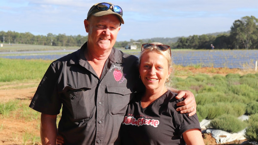 Man and woman standing in a paddock, smiling