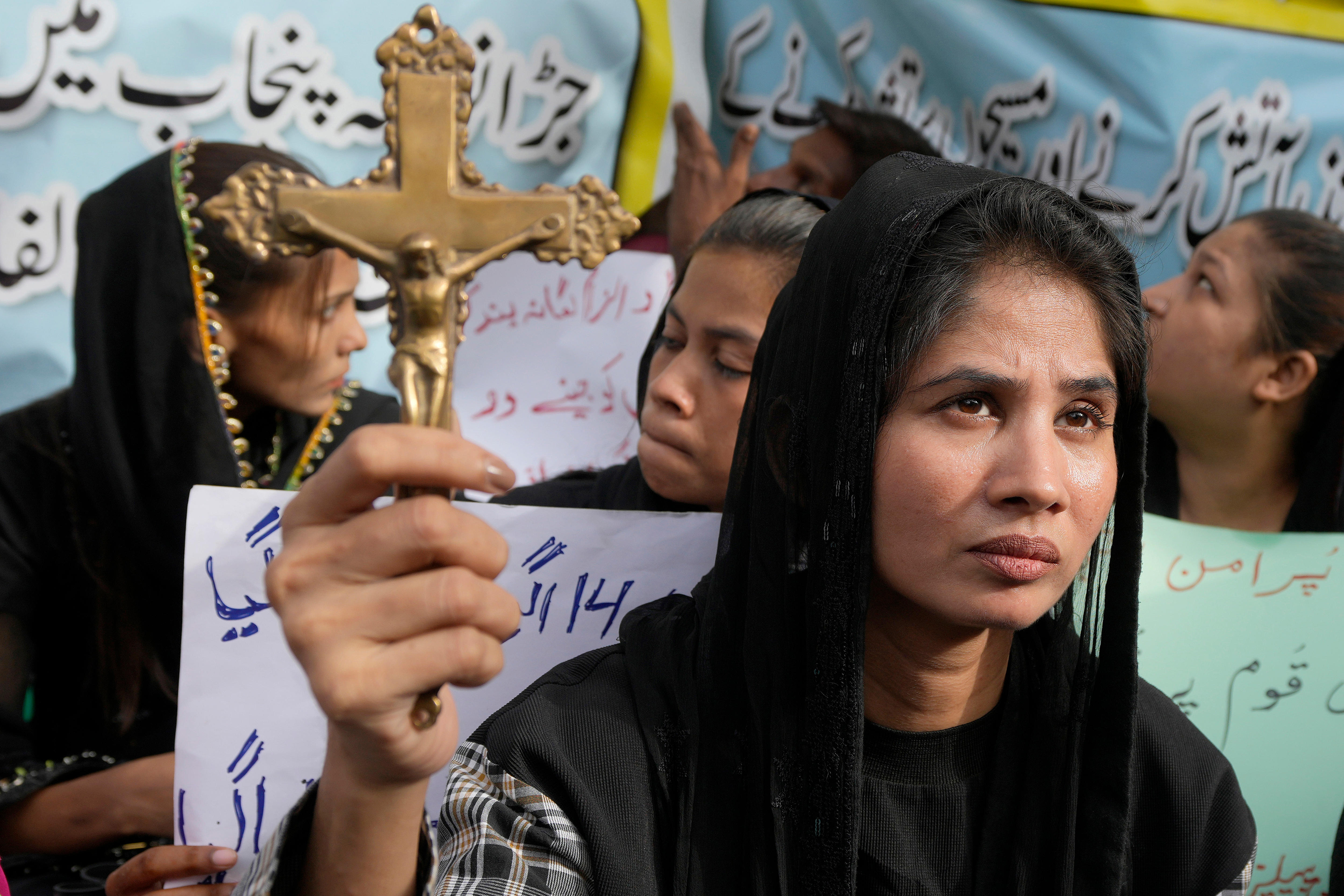 Woman holds up a golden cross in hand.