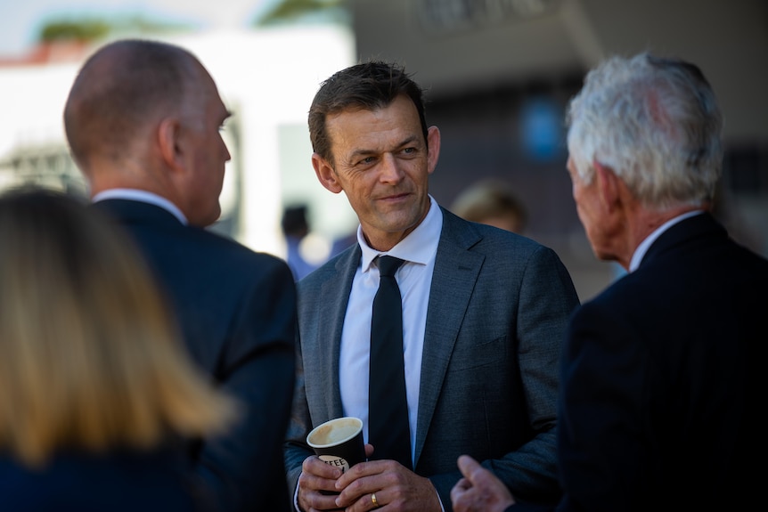 Former Australian cricket captain Adam Gilchrist talking to two men